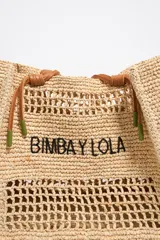 Bolso shopper de rafia trenzada color beige, con asas de cuero marrón y logo bordado en negro.