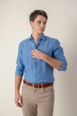 Camisa celeste de lino con cuello clásico y manga larga. Presenta un pequeño logo bordado en el pecho.