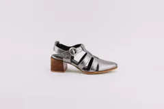 Sandalias plateadas de cuero con punta cerrada, tiras entrecruzadas y hebilla lateral. Taco de madera de 6,5 cm de altura.