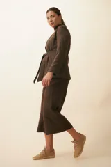 Chaqueta corta color beige, entallada, con escote en V, manga larga y cierre frontal con lazo fijo. Confeccionada en lana fina sin teñir, con bolsillos escondidos y terminaciones enviadas. Hecha 100% en Uruguay.