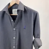 Camisa de vestir de algodón peletizado color azul grisáceo, de manga larga con puños abotonados y cuello clásico.