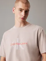 Remera color beige de corte regular, cuello redondo y mangas cortas. Presenta un monograma de Calvin Klein Jeans estampado en el pecho en color rojo y blanco.