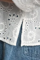 Blusa blanca de manga larga con cuello camisero, confeccionada en algodón con bordados calados (broderie) de diseño floral y arabesco.
