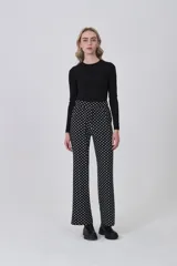 Pantalón de tiro alto, corte recto y largo, con estampado de lunares blancos sobre fondo negro.