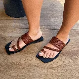 Sandalias chatas color marrón con tiras de cuero trenzado y base cuadrada negra.