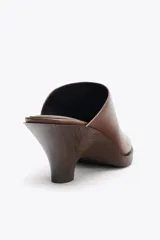 Zueco de cuero color marrón con tacón de 6 cm y detalle elástico lateral.