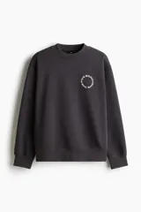 Buzo de algodón pesado color gris oscuro con efecto lavado e interior cepillado suave. Modelo con diseño estampado circular en el pecho, cuello redondo y hombros caídos. Remate acanalado en cuello, puños y bajo. Corte holgado.