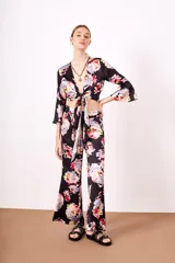 Camisa estampada con flores de colores sobre fondo negro, de corte cruzado, mangas 3/4 acampanadas y escote en V.