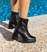 Botas cortas de cuero negro, con cierre lateral, taco de madera forrado en cuero y suela de goma.