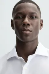 Camisa negra de manga larga con cuello italiano y cierre frontal de botonadura. Presenta un tejido con estructura de fácil cuidado.