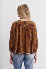 Camisa marrón con estampado floral y lentejuelas, escote en V y mangas largas abullonadas.