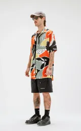 Camisa de manga corta con estampado abstracto en tonos naranja, negro, gris y amarillo. Tiene calce oversize y canesú en la espalda.