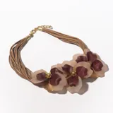 Collar corto con múltiples tiras de cuero sintético color beige y apliques de flores grandes en tonos rosa, borgoña y dorado.