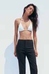 Pantalón negro de tiro alto con corte flare y cierre frontal con cremallera y gancho metálico.