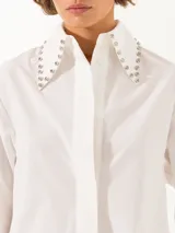 Camisa celeste de poplin, corte clásico, largo a la cadera y mangas largas. Cuello con detalle de piedras engarzadas. Cierre frontal con botones de pasta al tono.