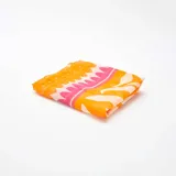 Pareo de baño rectangular con estampado de flores y ondas en tonos naranja, blanco y rosa.