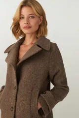 Chaquetón marrón de lana con cuello, abrochadura simple con botón en el cuello, bolsillos ojal y detalle de martingala en mangas.