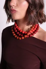 Collar de tres hilos con cuentas redondas de resina en tonos de rojo y naranja.