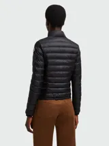 Chaqueta acolchada (tipo puffer) de color negro, con cuello alto y cierre frontal de cremallera. Presenta dos bolsillos frontales con solapa y cierre a presión.