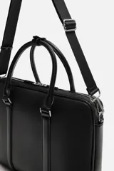 Maletín negro con textura grabada, cierre de cremallera, bolsillo interior para dispositivos electrónicos de hasta 13 pulgadas, bolsillo frontal con cremallera, doble asa de mano y asa de hombro ajustable y extraíble.