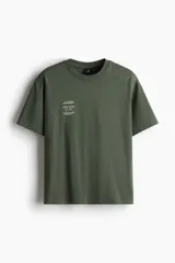 Remera verde militar de corte holgado con estampado frontal de texto y laureles en color blanco.