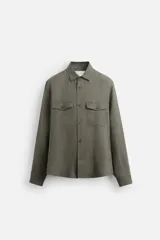 Sobrecamisa verde militar de lino, corte relaxed fit, con cuello solapa, manga larga con puños abotonados, bolsillos de parche con solapa en el pecho, aberturas laterales en el bajo y cierre frontal abotonado.