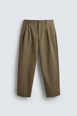 Pantalón color caqui de corte tapered relaxed fit, confeccionado en tejido de algodón. Presenta cintura con pliegues frontales dobles, bolsillos laterales en cadera y bolsillos traseros de vivo con botón. Cierre frontal con cremallera y botón.