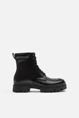 Bota negra de cuero con cordones, suela track y tirador trasero.