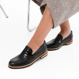 Mocasín de cuero vacuno color marrón, con detalle de antifaz en gamuza. Tiene taco de madera foliado en cuero de 2,5cm y entre suela de goma de 1cm.