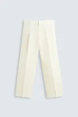 Pantalón color crema de lino, corte relaxed fit, con pliegues frontales, bolsillos laterales y traseros de vivo.