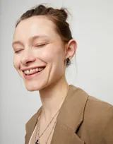 Par de aros plateados con cristal facetado grisáceo de forma ovalada.