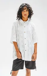 Camisa blanca con bordado floral, de corte amplio y mangas cortas.