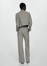 Pantalón de vestir acampanado color gris claro, de tiro alto, con cierre oculto de botón, gancho y cremallera, bolsillos laterales y costuras decorativas.