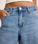 Bermuda de denim para mujer con cintura media y bajo deshilachado. Cuenta con trabillas en la cintura, cierre tradicional y bolsillos funcionales. Confeccionada en algodón con un toque de elastano.