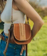 Bandolera de cuero color marrón con correa larga regulable, solapa con diseño trenzado y cierre con broche imantado.