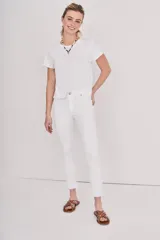 Pantalón jean blanco de corte slim, tiro alto y terminación desflecada en el ruedo.