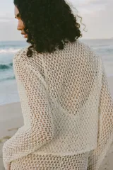 Top color crudo de tejido crochet calado, con cuello redondo y mangas largas.