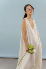 Vestido largo confeccionado en lino de color beige, con escote en V, diseño sin mangas y silueta holgada de caída fluida.