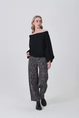 Sweater holgado de tejido ligero, color beige claro, con escote asimétrico que deja un hombro al descubierto.