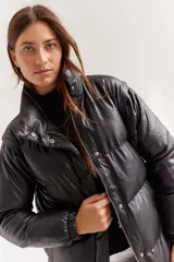 Campera puffer negra de cuero sintético, con cuello alto, cierre frontal con cremallera y botones a presión, y bolsillos laterales.