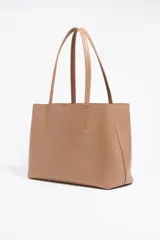 Bolso shopper negro de cuero con textura granulada, doble asa de hombro y logo blanco estampado en la parte inferior. Interior color caramelo con bolsillo con cierre. Cierre superior con lazo de cuero.