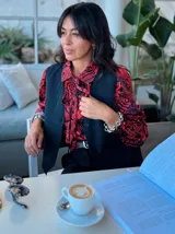 Blusa de manga larga con estampado de flores rojas y negras, cuello con lazo y corte holgado.