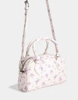 Cartera bowling de cuerina color blanco con estampado de mariposas lilas, doble asa corta y correa larga regulable y desmontable.