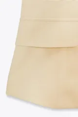 Top chaleco color crema, con escote recto, sin mangas, detalle de solapas y cierre frontal con botones dorados.