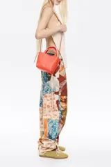 Bolso de mano mini de piel vacuna color blanco roto, con textura granulada. Presenta asas superiores y cordones ajustables laterales. El logo metálico de Bimba y Lola está grabado en el frente.