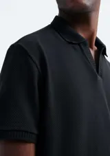 Camisa polo de piqué negro con cuello clásico y tapeta de dos botones.