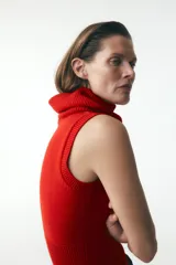 Chaleco de punto color crudo, con cuello alto y sisa amplia.