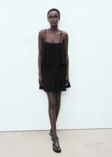 Vestido corto negro con tirantes finos, escote recto y falda con volados.