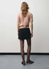 Sweater de punto color rosa, con cuello alto y mangas cortas.