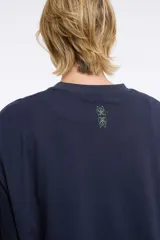 Remera blanca de algodón con cuello redondo y manga corta. Estampado pequeño de un ají rojo en el centro del pecho.